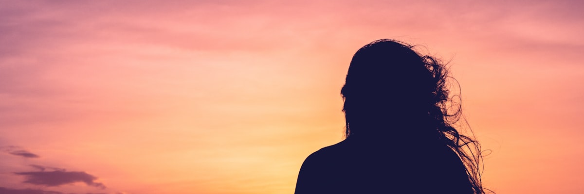 窓の外を見つめ考える女性の後ろ姿