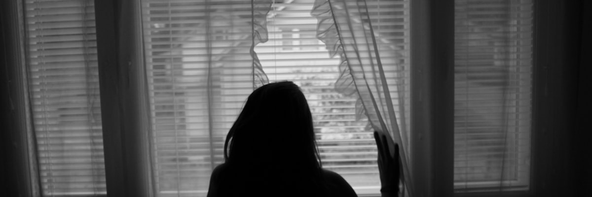 窓辺で外を見つめる女性の後ろ姿