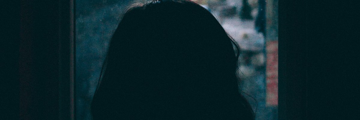 窓の外を見ながら考える女性の後ろ姿