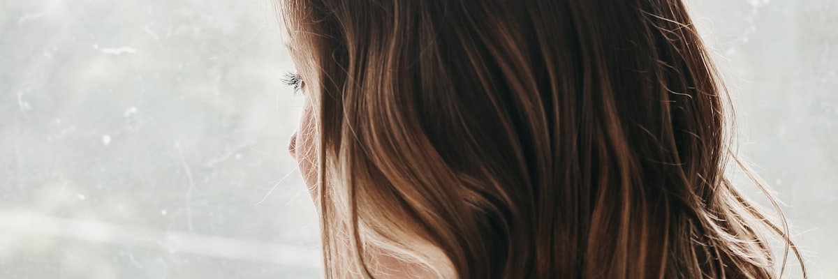 不安を抱えながら窓の外を見つめる女性の後ろ姿