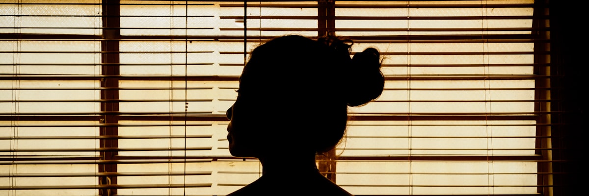 窓の外を見ながら考える女性の後ろ姿