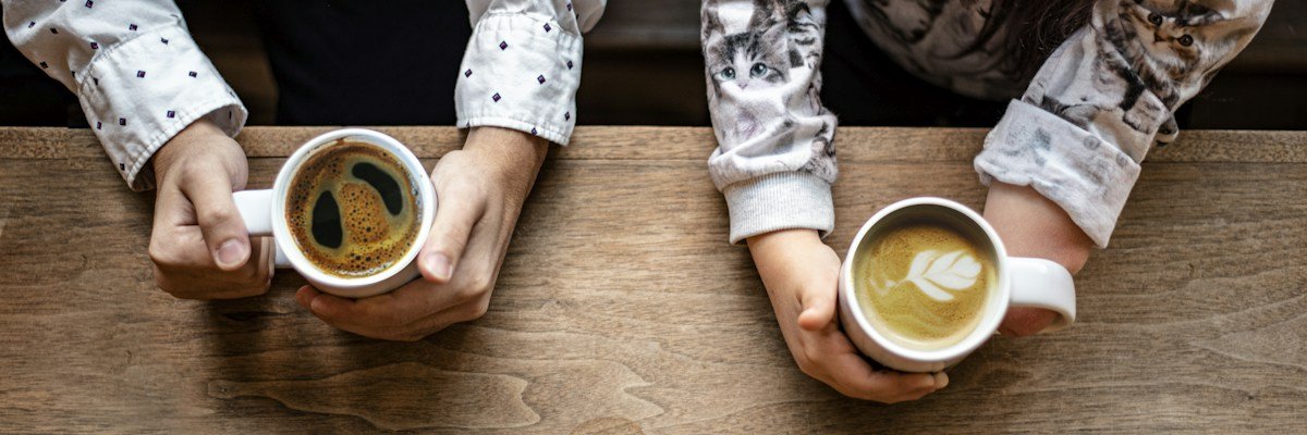 コーヒーを手に話す二人の手元