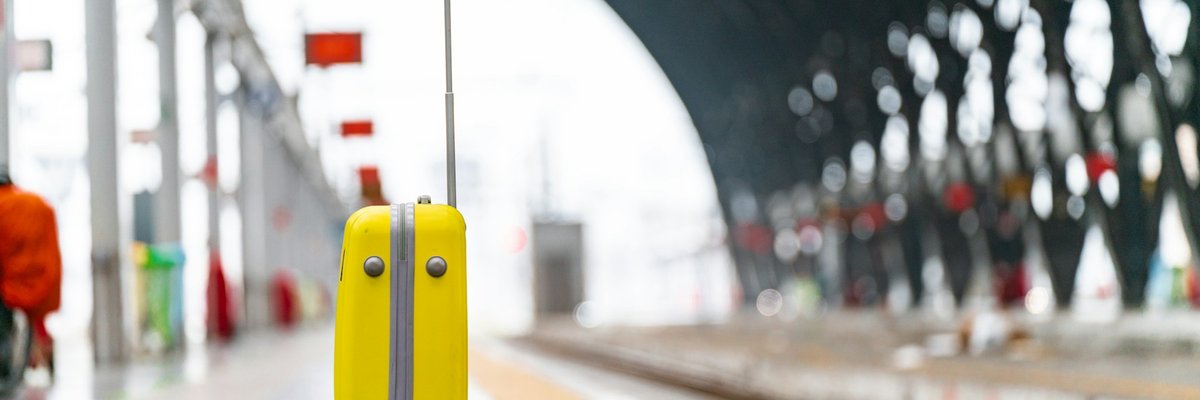駅のホームに立つ黄色いスーツケース