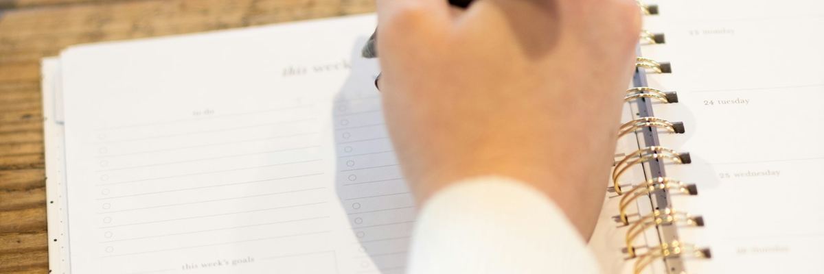手帳に予定を書き込む女性の手元